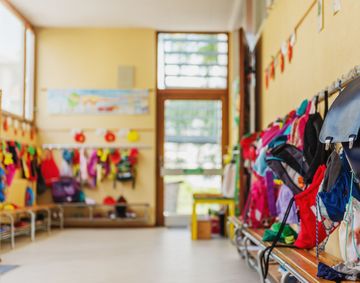 Empty hallway in the school, backpacks and bags on hooks, bright recreation room