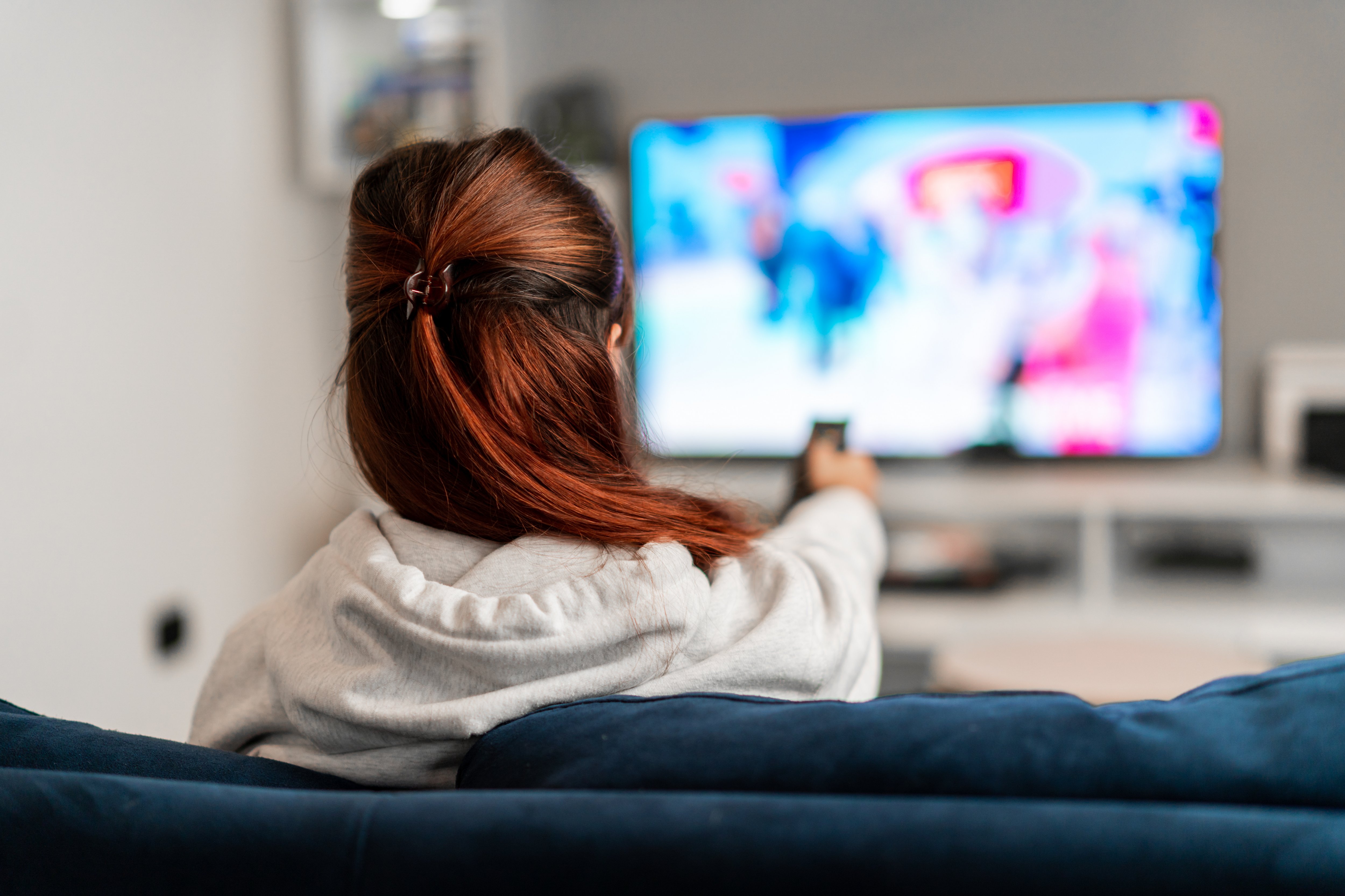 Frau sitzt auf dem Sofa und schaut fern